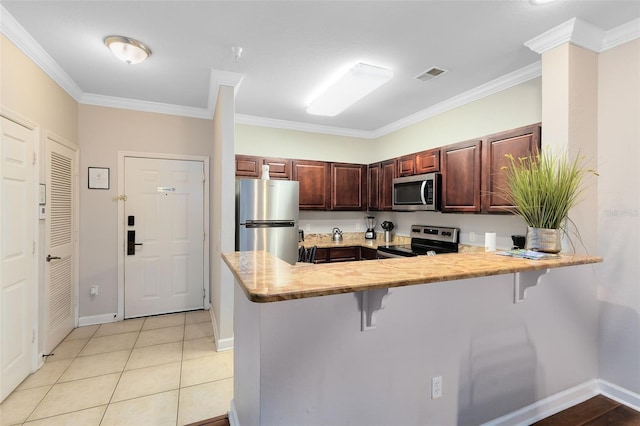 kitchen with a kitchen breakfast bar, ornamental molding, and stainless steel appliances