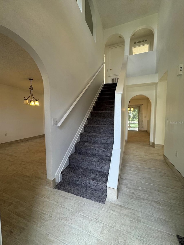 staircase featuring wood-type flooring and a notable chandelier