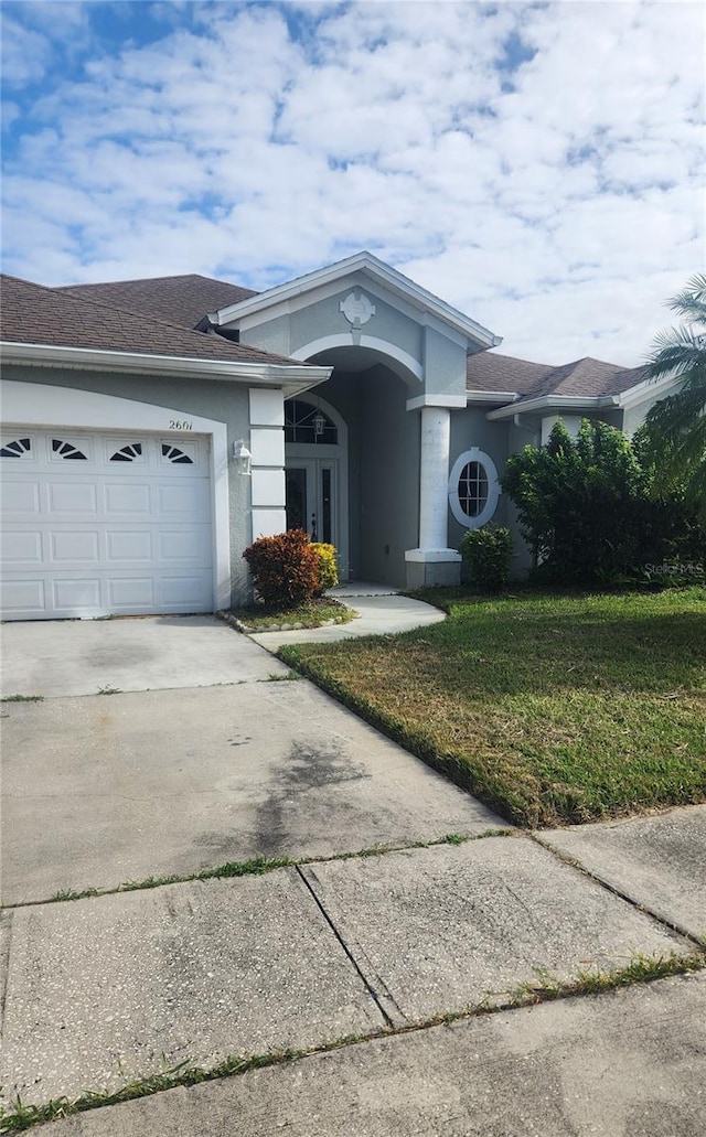 view of front of home featuring a front lawn, a garage, and french doors