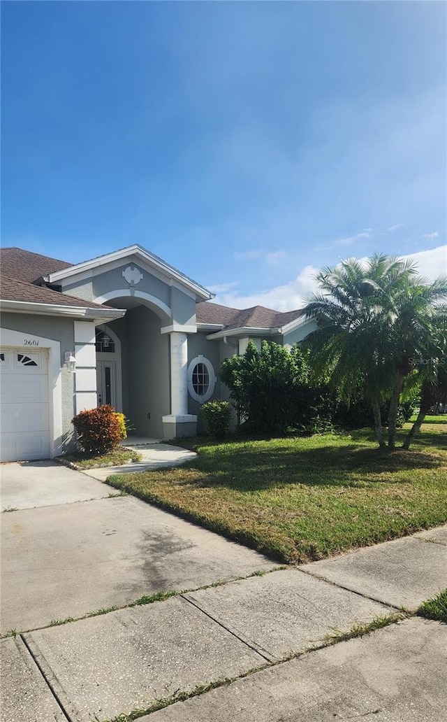 ranch-style house with a garage and a front lawn