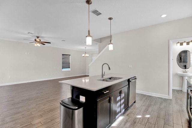 kitchen with sink, hanging light fixtures, stainless steel dishwasher, an island with sink, and light hardwood / wood-style floors