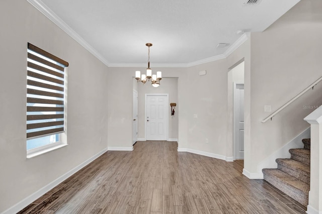 entrance foyer featuring wood-type flooring, crown molding, and an inviting chandelier