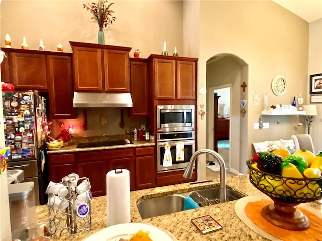 kitchen featuring appliances with stainless steel finishes, light stone counters, and sink