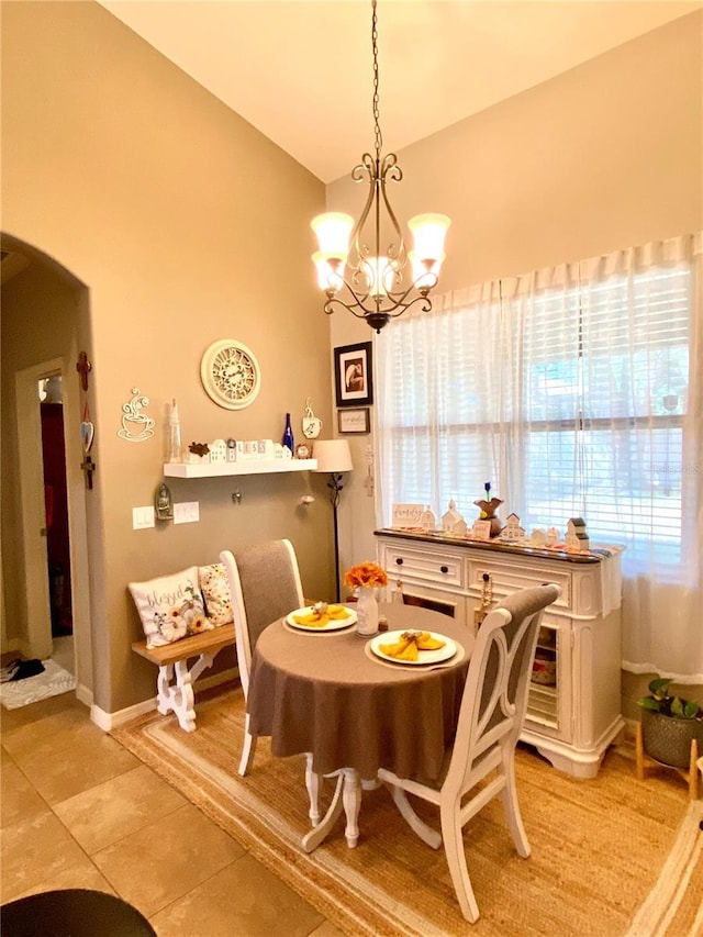 dining space with light tile patterned flooring, lofted ceiling, and a chandelier