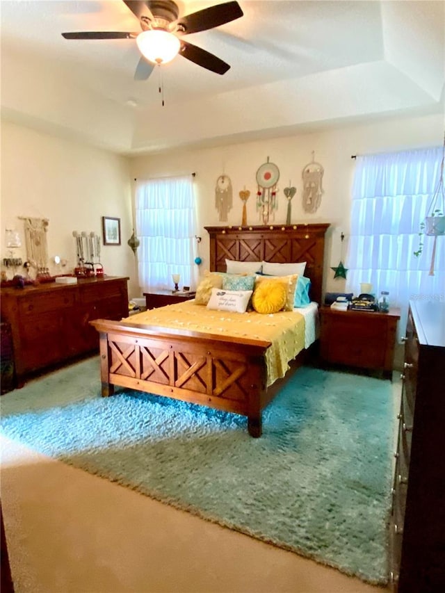 bedroom featuring carpet, a raised ceiling, and ceiling fan