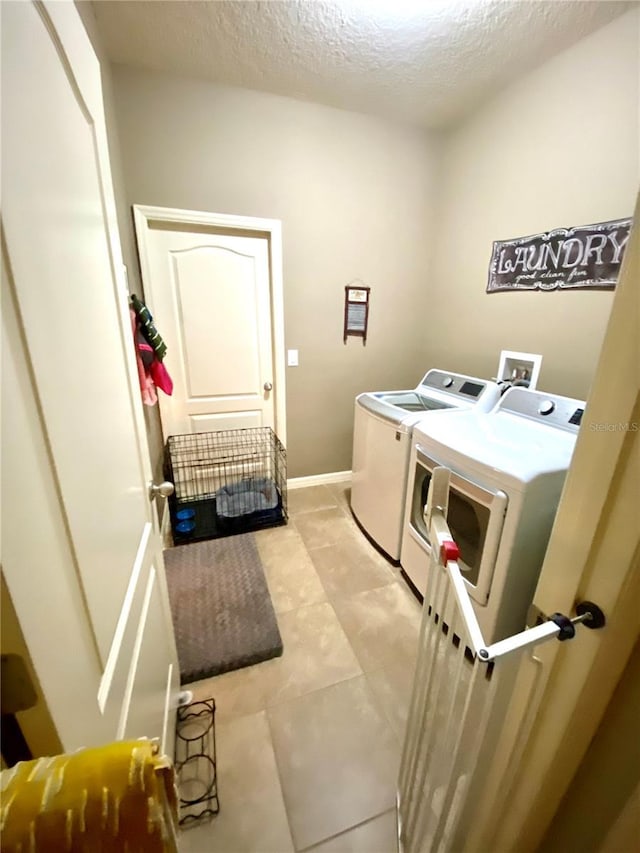 laundry room featuring independent washer and dryer, a textured ceiling, and light tile patterned flooring