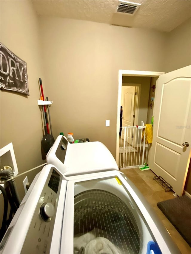 laundry area with a textured ceiling and washing machine and dryer