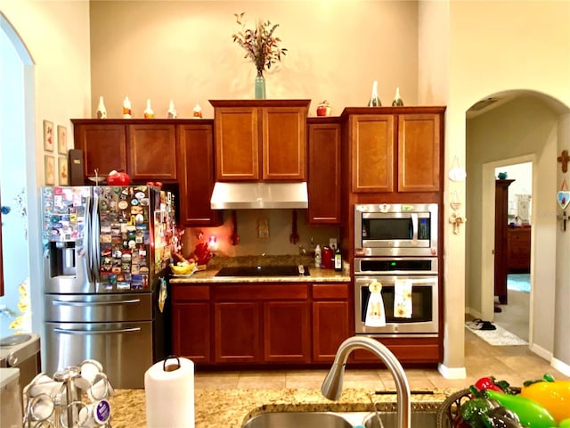 kitchen featuring light stone counters, sink, light tile patterned floors, and appliances with stainless steel finishes