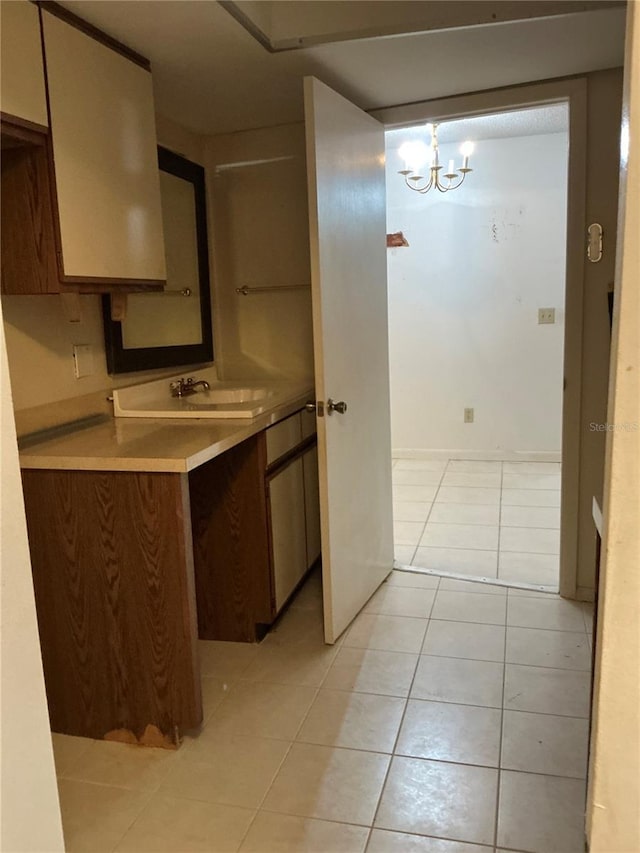 kitchen featuring sink, light tile patterned floors, pendant lighting, and a notable chandelier