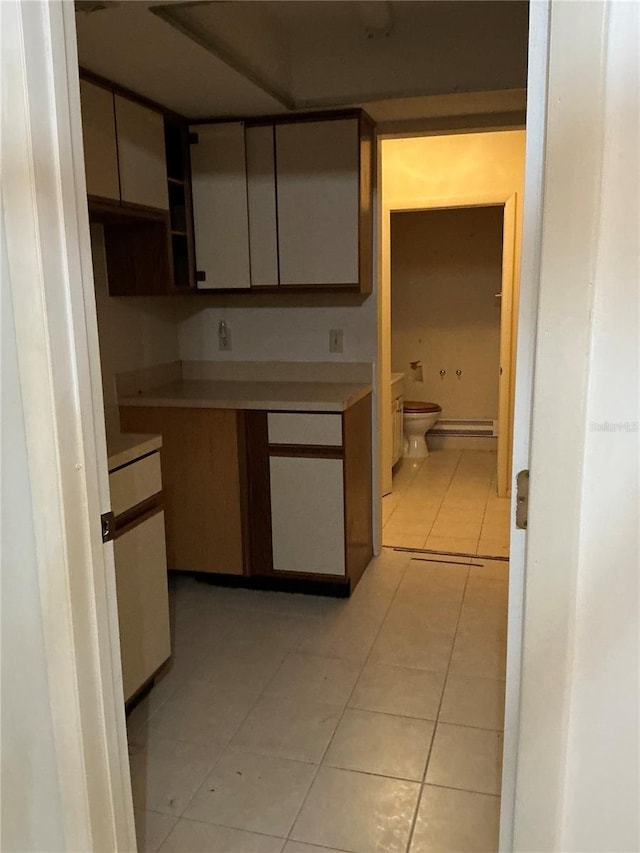 kitchen with baseboard heating and light tile patterned floors