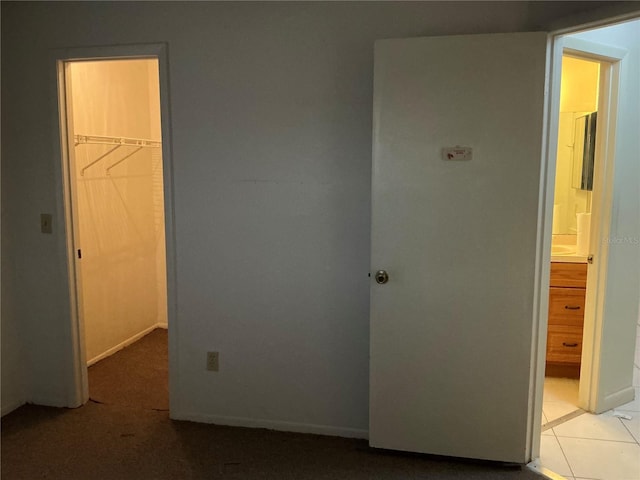 unfurnished bedroom featuring a walk in closet, a closet, and light tile patterned floors