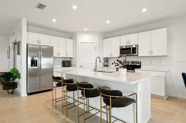 kitchen featuring white cabinetry, a kitchen island with sink, sink, and appliances with stainless steel finishes