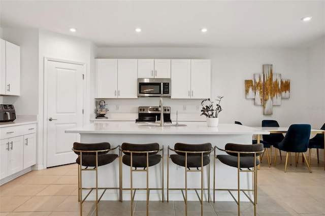 kitchen featuring a center island with sink, white cabinetry, a breakfast bar area, and sink