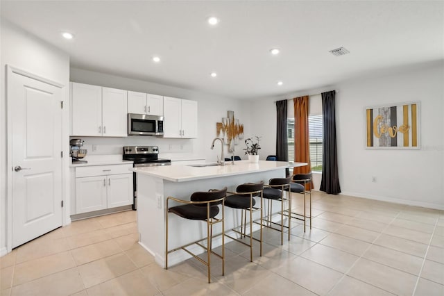 kitchen with white cabinetry, a kitchen island with sink, a breakfast bar area, and appliances with stainless steel finishes