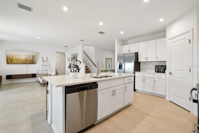 kitchen with stainless steel appliances, white cabinetry, a center island with sink, and sink