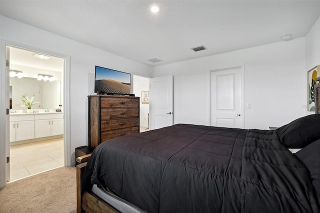 bedroom featuring ensuite bathroom, sink, and light carpet