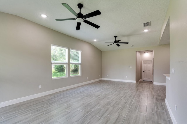 empty room featuring a textured ceiling, vaulted ceiling, ceiling fan, and light hardwood / wood-style flooring