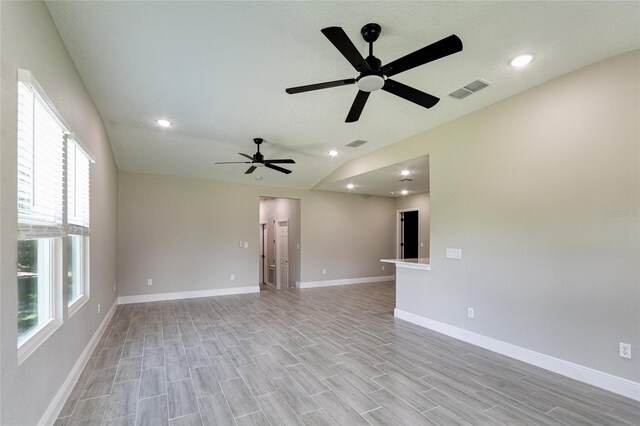 unfurnished room featuring a healthy amount of sunlight, vaulted ceiling, and light hardwood / wood-style floors