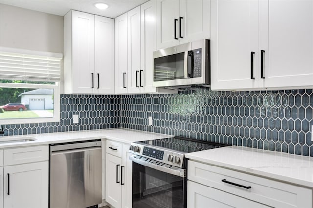 kitchen with light stone countertops, white cabinets, decorative backsplash, and stainless steel appliances