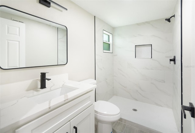 bathroom featuring toilet, vanity, tile patterned flooring, and tiled shower