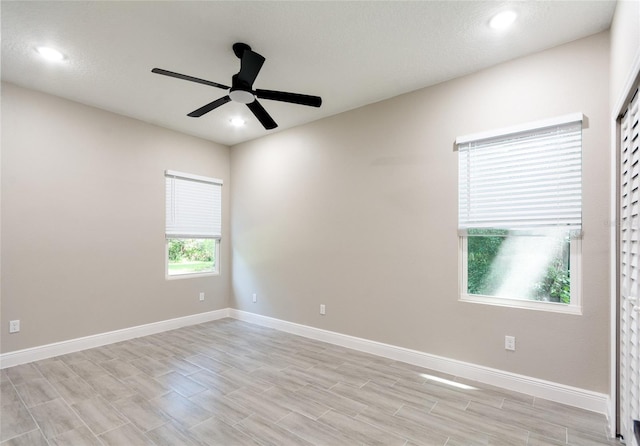 spare room with a textured ceiling, light wood-type flooring, and ceiling fan