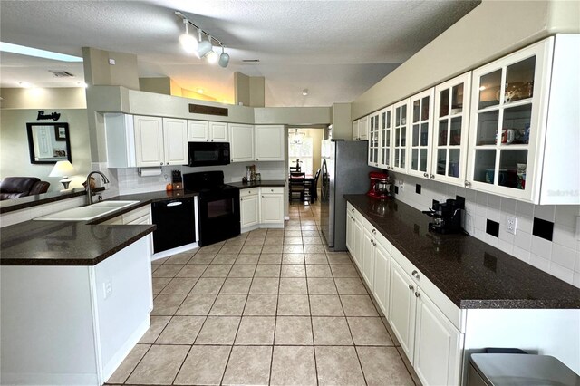 kitchen with kitchen peninsula, backsplash, black appliances, white cabinetry, and lofted ceiling