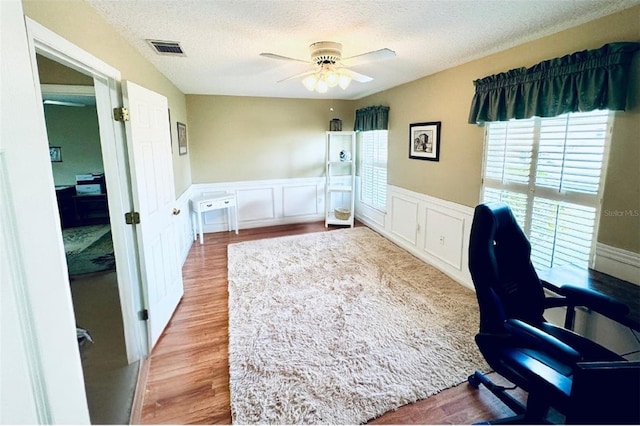 office area with a textured ceiling, light hardwood / wood-style floors, and ceiling fan