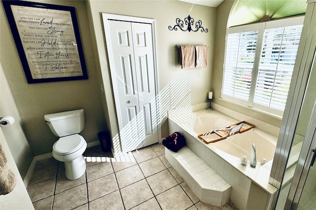 bathroom featuring tiled bath, tile patterned flooring, and toilet