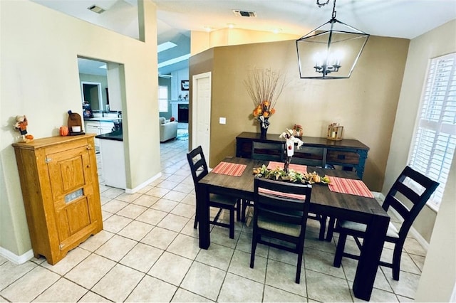 tiled dining space featuring a notable chandelier and lofted ceiling