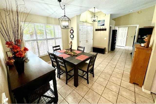 dining space featuring a textured ceiling, light tile patterned floors, vaulted ceiling, and an inviting chandelier