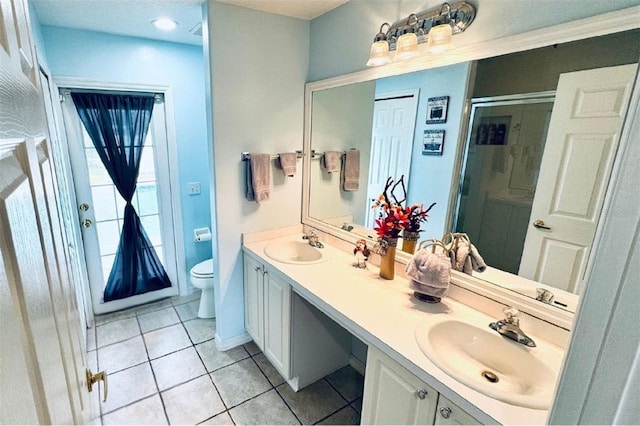 bathroom featuring tile patterned flooring, vanity, toilet, and a shower with door