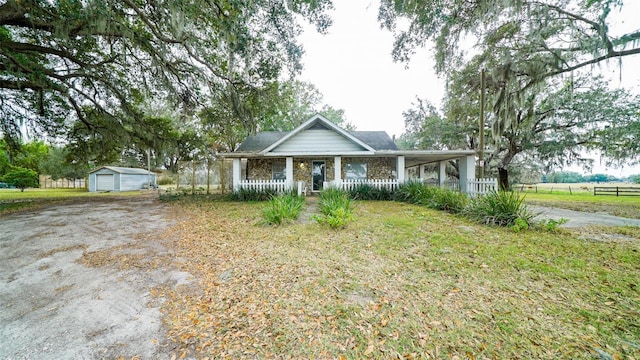 view of front of home with covered porch, a garage, and an outbuilding