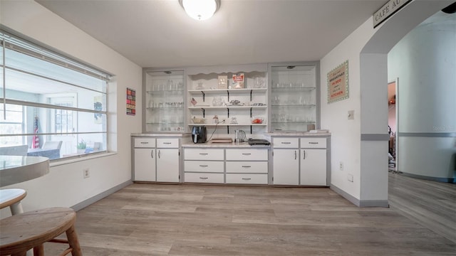 bar featuring light hardwood / wood-style flooring and white cabinets