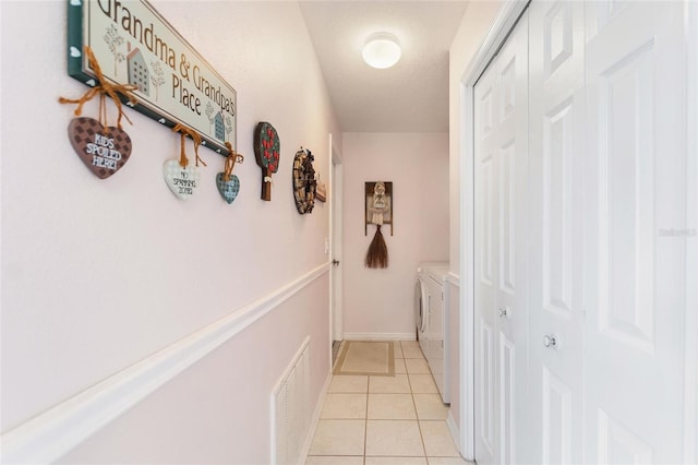 hallway with washing machine and dryer and light tile patterned floors