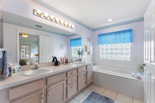 bathroom with tile patterned floors, ornamental molding, vanity, ceiling fan, and a relaxing tiled tub