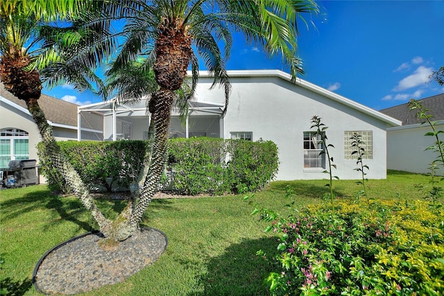 view of side of property with a lanai and a lawn