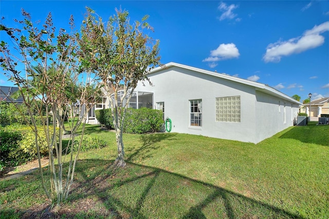 rear view of property with cooling unit, a lanai, and a lawn