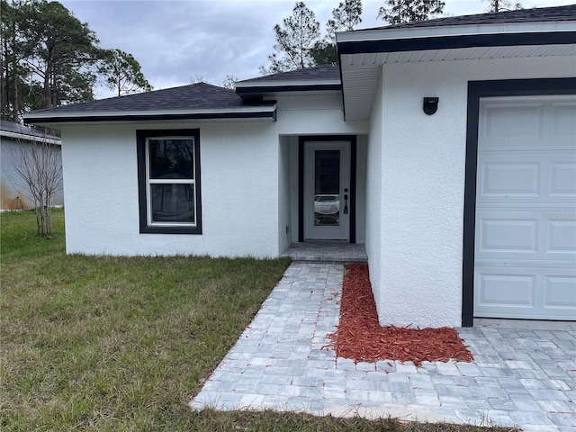 doorway to property with a garage and a lawn