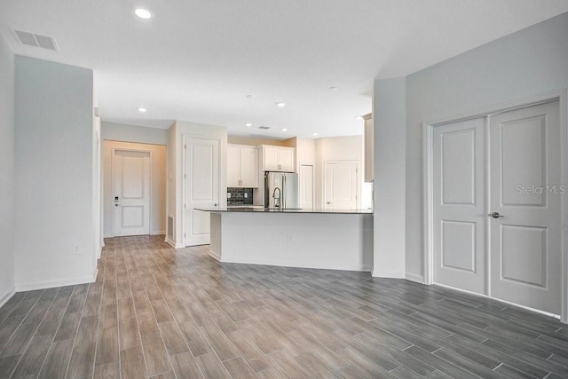 unfurnished living room featuring hardwood / wood-style floors and sink