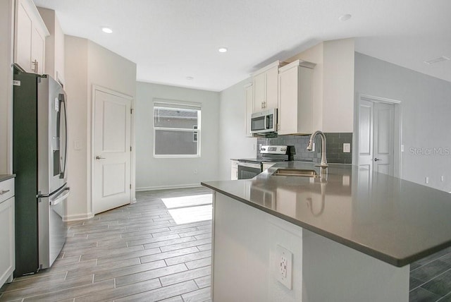 kitchen with white cabinetry, appliances with stainless steel finishes, sink, and light wood-type flooring