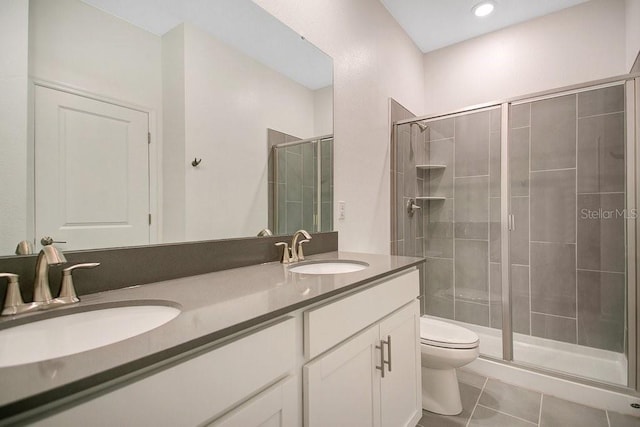 bathroom featuring toilet, vanity, tile patterned flooring, and a shower with door