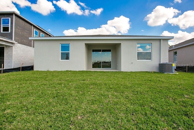 rear view of property with central air condition unit and a lawn