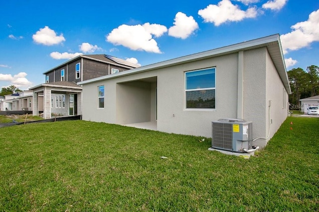 back of house with central air condition unit and a yard