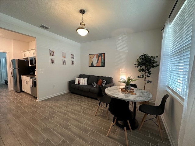 dining area with a textured ceiling and dark hardwood / wood-style floors