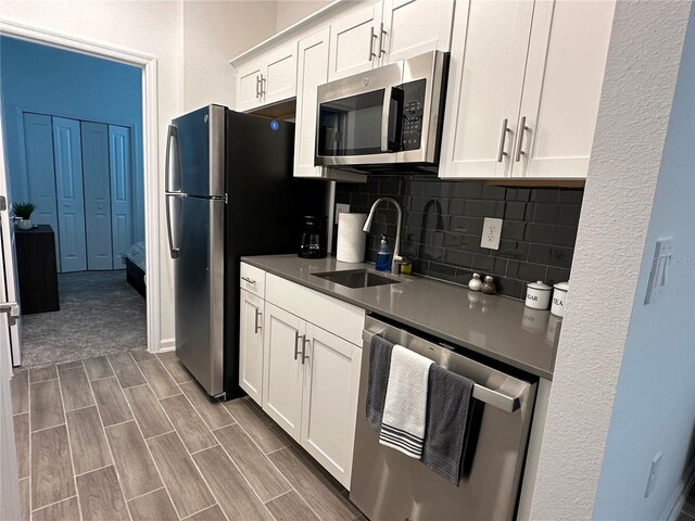 2971 Camden Way, Davenport, FL 33837 - kitchen with stainless steel appliances, a sink, backsplash, dark countertops, and white cabinetry
