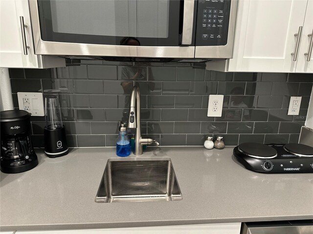 2971 Camden Way, Davenport, FL 33837 - kitchen featuring stainless steel microwave, backsplash, white cabinets, a sink, and light countertops
