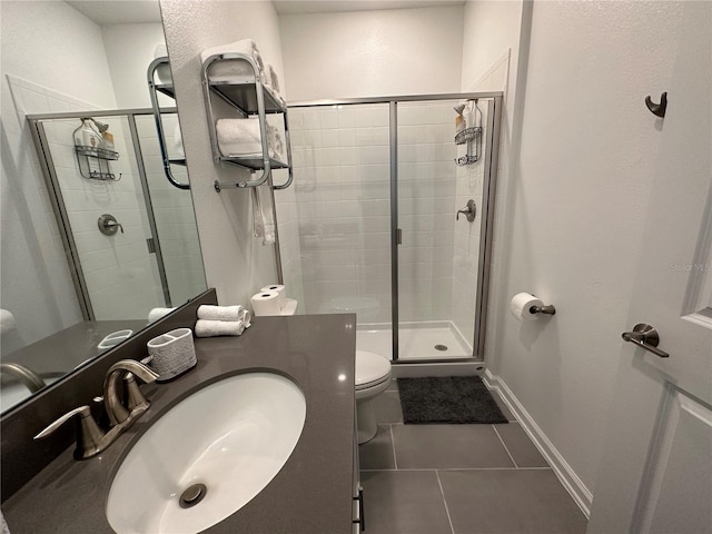 bathroom featuring toilet, vanity, tile patterned floors, and a shower with shower door