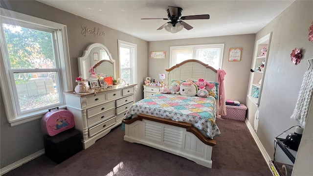 bedroom with multiple windows, ceiling fan, and dark carpet