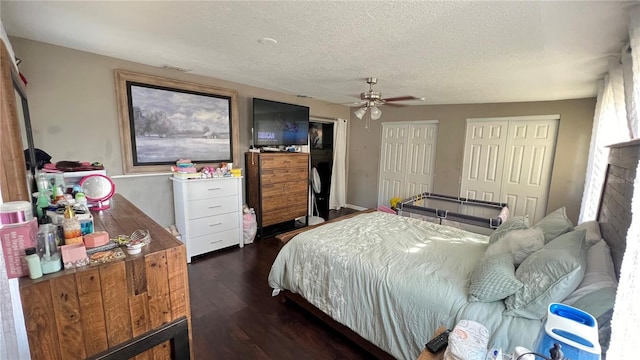 bedroom featuring ceiling fan, a textured ceiling, multiple closets, and dark hardwood / wood-style flooring