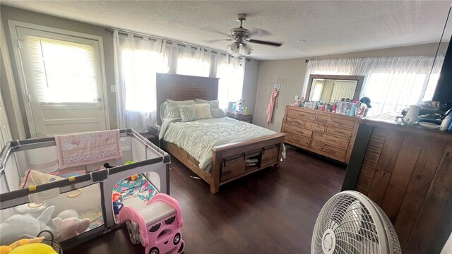 bedroom with dark hardwood / wood-style floors, ceiling fan, multiple windows, and a textured ceiling